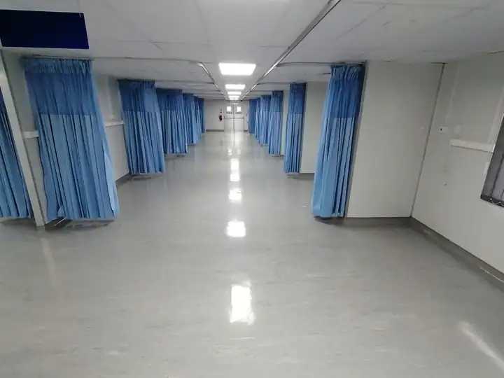 Covid ward with bed bays and blue privacy curtains